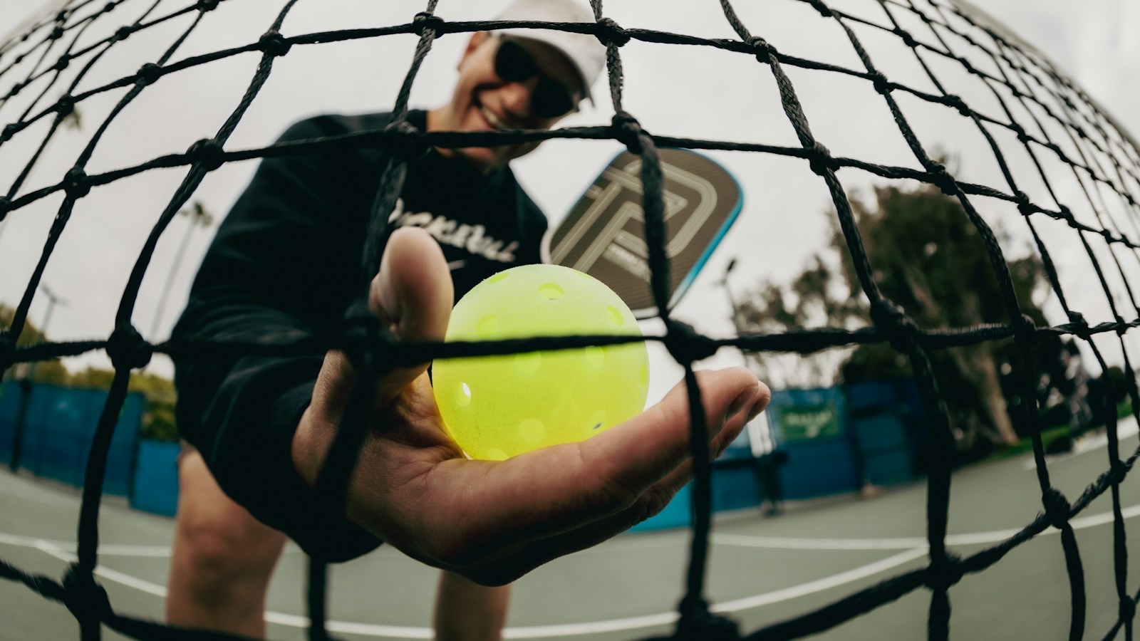 Pickleball player on court with a paddle and ball